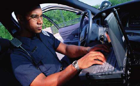 Police officer using a laptop in his vehicle