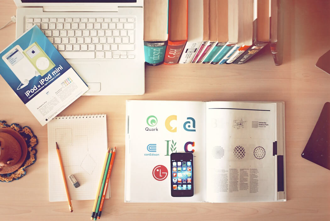 Books, a notebook, and Apple products on a desk